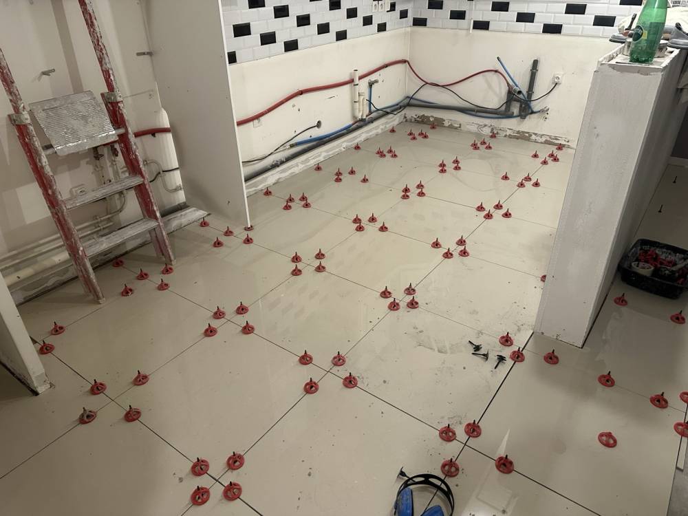 Pose d'un carrelage grand format 60x60 avec système de nivellement dans une cuisine ouverte en rénovation à Vigneux-sur-Seine par HOME Éditions.